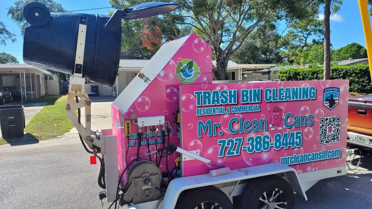 Mr. Clean Cans trailer cleaning a trash bin curbside on its crane arm